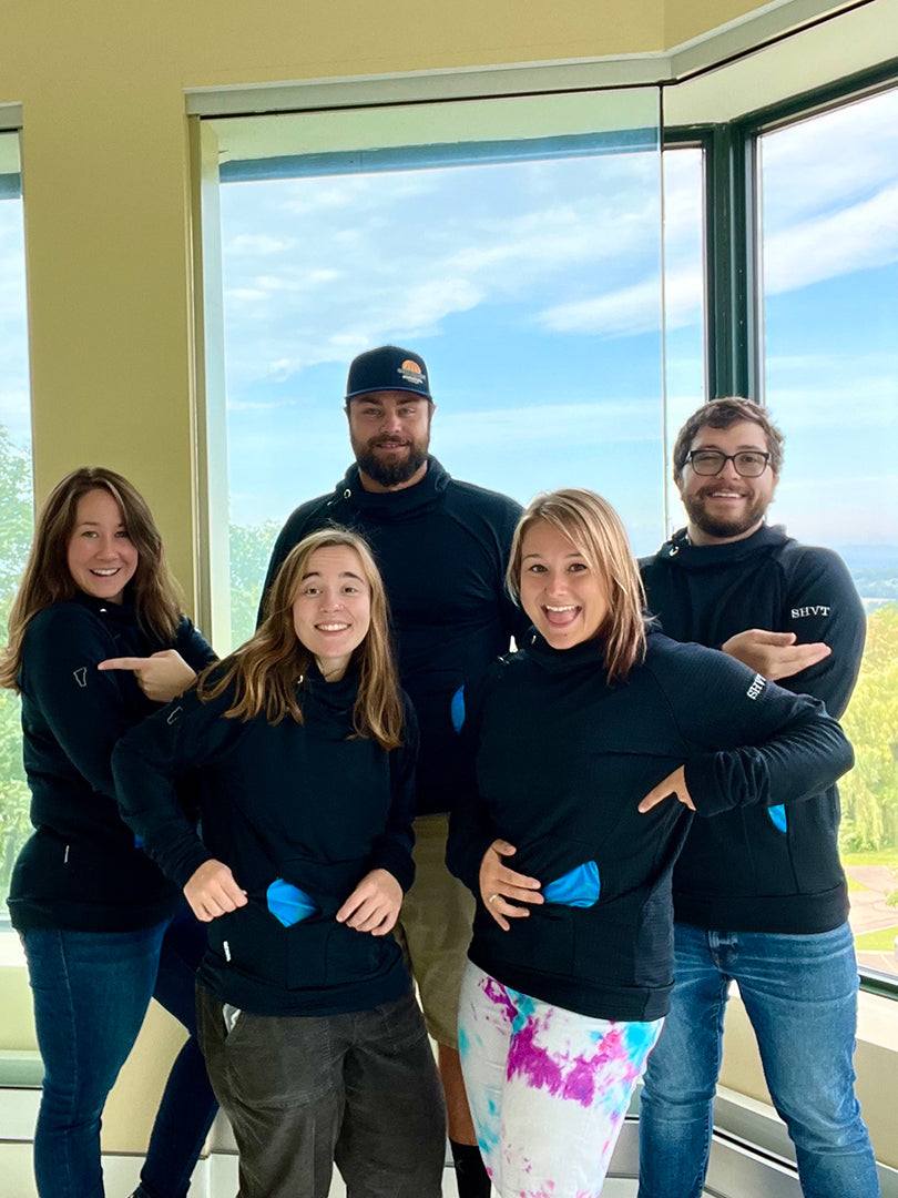 A group of Steep Hill Vermont employees pose wearing Custom Thuja Burrow fleece hoodies that feature sleeve embroidery and unique THC pocket patterns.