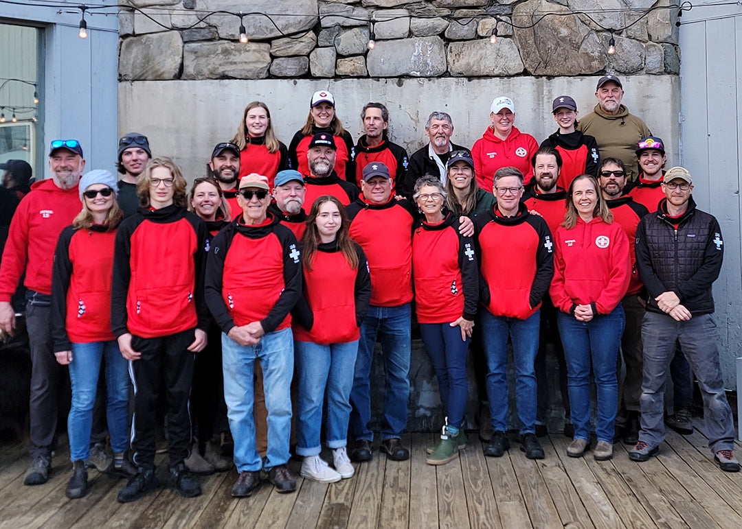 A group of Saskadena Six (S6) Ski Patrollers wearing black and red custom embroidered Thuja Burrow fleece hoodies.